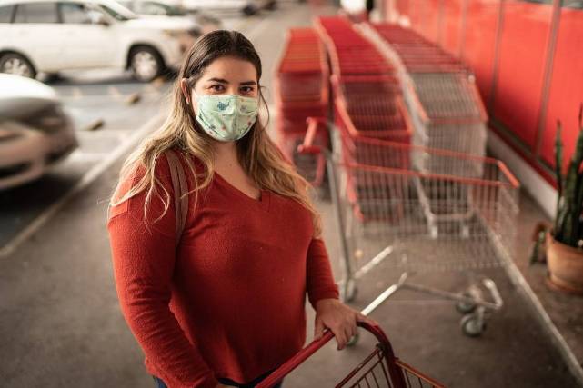 Hispanic women in red shirt and mask, shopping with a cart in Florida